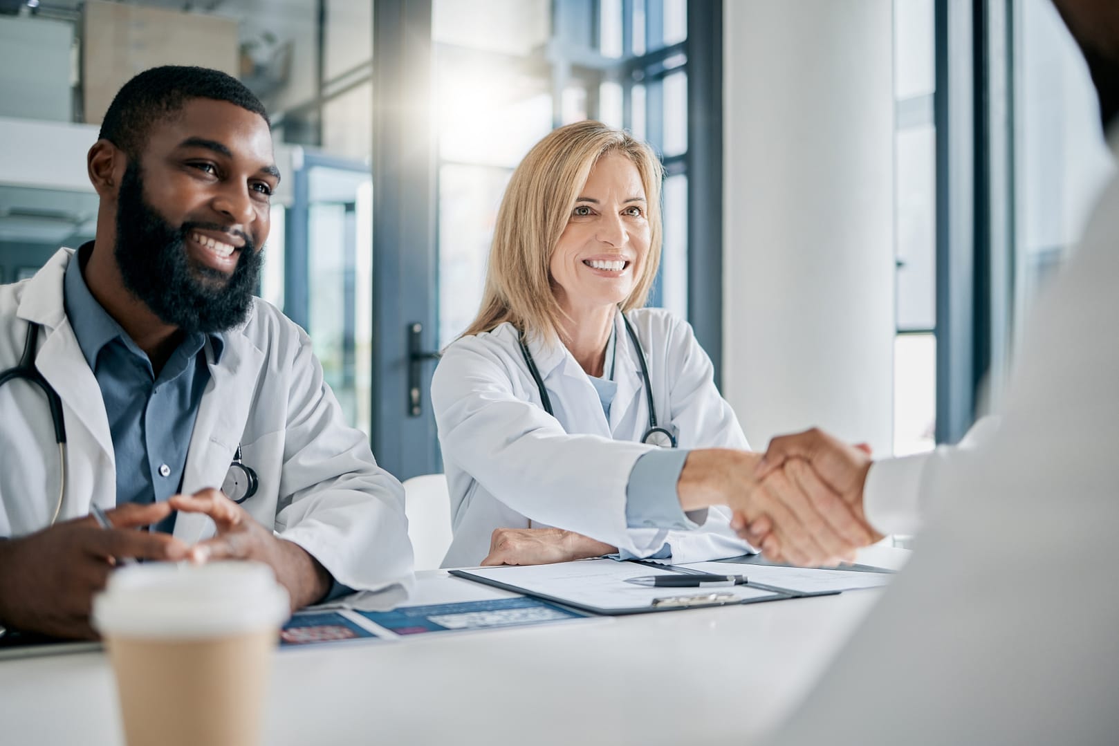 Doctors and employers shaking hands in a meeting to symbolize a value-based care partnership